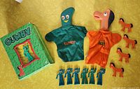 Green box with Gumby logo beside Gumby and Pokey puppets and smaller figurines.