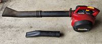 Homelite Vac Attack II gas leaf blower with long nozzle attached and extra short nozzle attachment shown separately on concrete surface