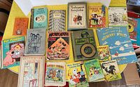 Overview of 18 vintage children's books laid out on table showing colorful illustrations and titles.