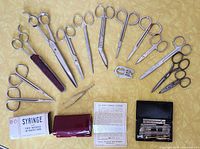 Overview of all scissors, tweezers, syringes and accessories arranged on a surface.