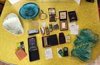 Full view of all lot items arranged on yellow tablecloth, showing lighters and ashtrays.
