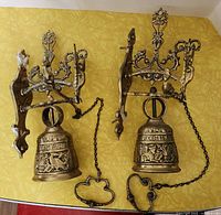 Pair of brass bells mounted on yellow surface showing full lot