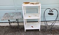 Photo showing an antique wicker folding table with rusted wicker surface next to a white painted metal 3-shelf table with visible rust spots and paint wear.