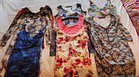 Full lot of 7 women's dresses laid flat showing variety of colors, patterns, and sleeve types.