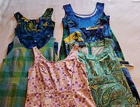 Top view of five women's dresses arranged flat showing floral, tropical, check, and paisley patterns