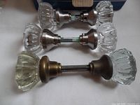 Three vintage glass door knobs, two with silver-tone fittings paired, one with brass-tone fitting separate, showing glass details and metal stems