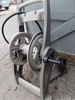 Side view of plastic hose reel cart with wheels and handle, hose partially wound.