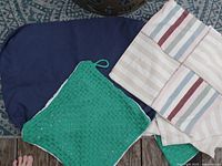 Nine assorted Ikea cushion covers on a patterned rug including dark blue and green woven outdoor covers and striped cotton covers.