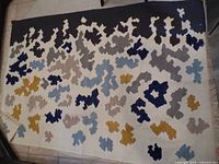 Overview of the wool rug showing full rectangular shape and abstract colored patterns on off-white background