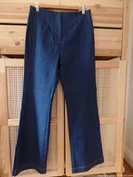 Full front view of dark blue denim trouser jeans hanging with front darts and clean finished hem.