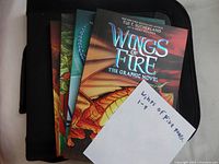 Front covers of Wings of Fire graphic novels fanned out showing colorful dragon artwork