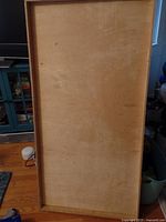 Photo showing the entire large wooden tray with natural finish and raised edges, resting on a hardwood floor near furniture.