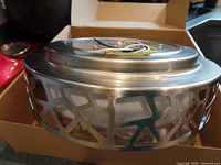 Top angle photo showing the decorative metal outer frame with geometric cutout pattern and wiring for installation.