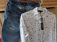 Photo of the white star print shirt alongside the blue distressed jeans, showing size details and tags.