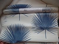 Rolled unopened peel and stick wallpaper showing blue palm leaf design.