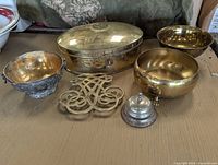 Full group shot showing six brass and metal decorative items grouped on a surface.