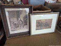 Pair of framed antique art prints showing different scenes; one horse-drawn carriage with passengers, other man with dog near rustic building. Both frames and prints show signs of wear and soiling.