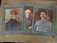 Three antique French military general portrait prints laid out on a wooden surface, showing visible wear and edge damage.