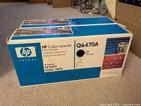 Photo showing two sealed boxes of HP Color LaserJet black toner cartridges, model Q6470A, for HP CP3505 and 3600-3800 series printers.