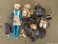 Full view of the Jane West cowgirl doll surrounded by all western-themed accessories including hats, holsters, boots, pouches, and vests.
