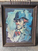Framed vintage art print of a sad clown with blue hat and red bow tie, frontal view.
