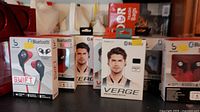 Photo showing multiple boxes of earphones and headphones from brands Verge and Swift on table.