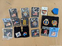 Photo showing the full collection of vintage Olympic pins and gold tone medal on wooden surface.