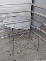 Full view of vintage West Elm side table with triangular mirrored top, showing wear and the thin intersecting chrome legs forming a geometric base.