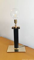 Full lamp view showing brass base, black leather body, and exposed bulb