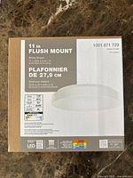 Front view of the box showing product name '11 in Flush Mount', model number, white finish, dimensions (11 inches diameter, 2.6 inches height), and LED details.