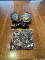 Full lot overview showing two large agate slices, polished dolphin carving, and bag of assorted stones on wooden surface.