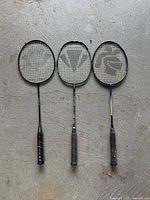 Three badminton rackets laid side-by-side showing full length and grips.