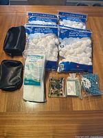 Photo showing all items in the lot including makeup bags, cotton balls, cotton pads, soap, soap holder, and shower cap laid out on a wooden surface.