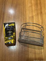 Photo showing box of got2b Ultra Glued hair gel and metal mesh bathroom organizer on wooden surface.