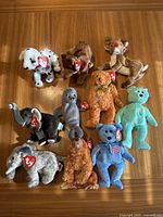 Full view of all 10 Beanie Baby plush toys laid out on wood surface all with original TY tags.