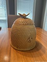 Full view of the cookie jar showing the honeycomb texture and bumblebee decoration on front with lid featuring a bumblebee handle.