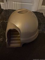 Closed dome shaped cat litter box in grey showing the entrance and top surface