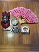 Photo of entire lot showing mask, plate, fan, coasters box, ashtray, and hair clip arranged on table