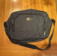 Front view of the black Jetstream travel bag with front zippered compartment and logo.