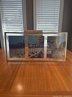 Front view of the Umbra gold three picture frame holding three photos in vertical arrangement separated by metal dividers.