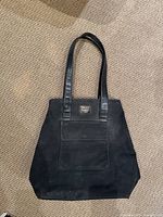 Full view of vintage black DKNY suede tote bag with leather handles, placed on carpet showing overall shape and condition.