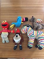 Front view of all five vintage stuffed animals laid out on wood surface