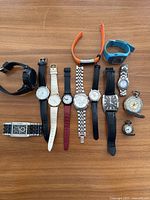 Photo of 11 watches arranged in three rows showing variety of styles, including digital, analog, metal, leather, silicone straps, and two pocket watches