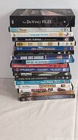 Stack of 15 DVD cases showing titles including The Da Vinci Files, Smurfs, Mary Poppins, Baby Einstein, and others.