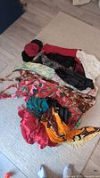 Full view of the entire clothing lot laid out on a floor showing dresses, scarves, and hats.