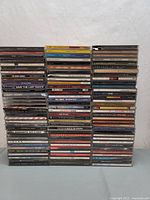 Photo showing multiple stacks of DVD cases with visible artist names and titles, primarily rock genre and classical music.