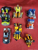 All six Transformers toys displayed on red fabric background.
