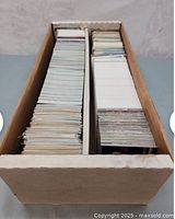 Cardboard box full of hockey cards organized into two sections inside the box, showing large quantity and storage method.