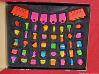 Top-down view of black foam insert in collector box with around 40 colorful miniature Shopkins figures arranged in rows.