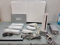 Complete Nintendo Wii system components including console, controllers, sensor bar, balance board, manual, and cables.